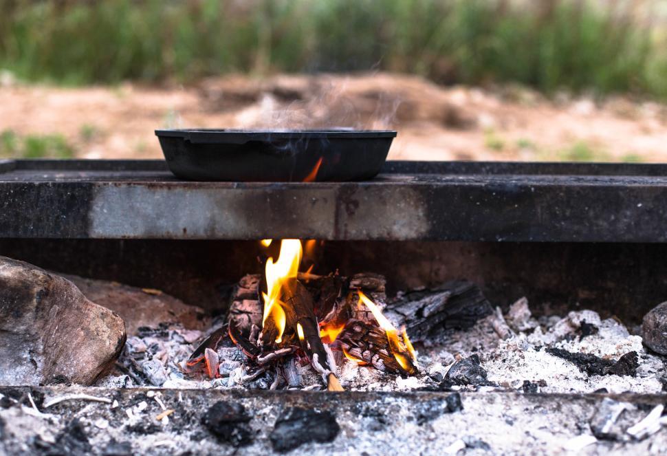 Free Image of Campfire with pan placed on grill cooking at a campsite. 