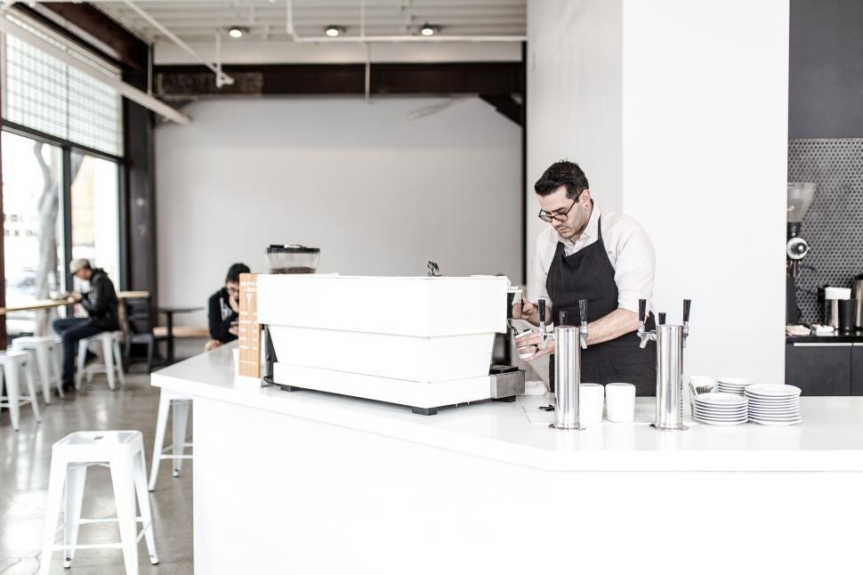 Free Image of Barista preparing coffee behind a modern counter. 
