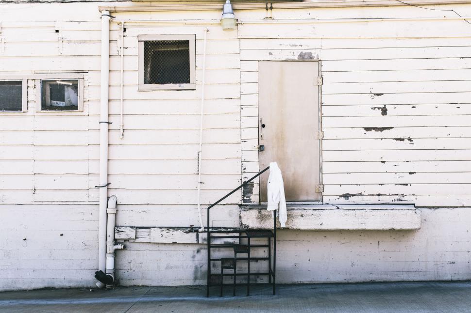 Free Image of Front view of a worn, white wooden house exterior. 