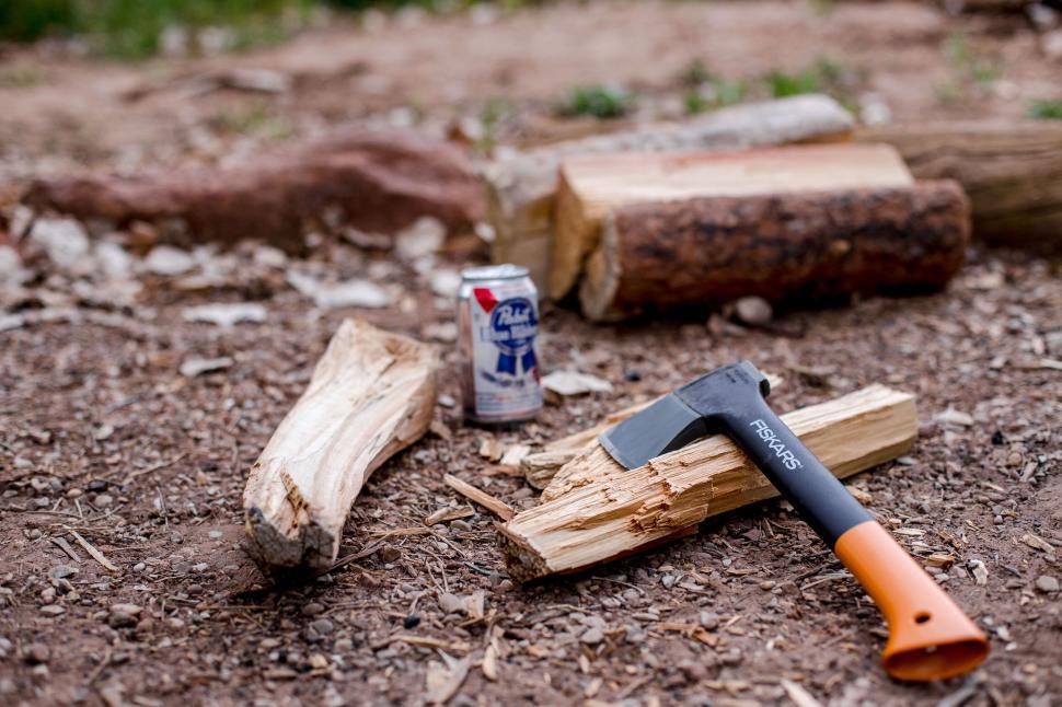 Free Image of Outdoor scene with axe, logs, and beer can. 
