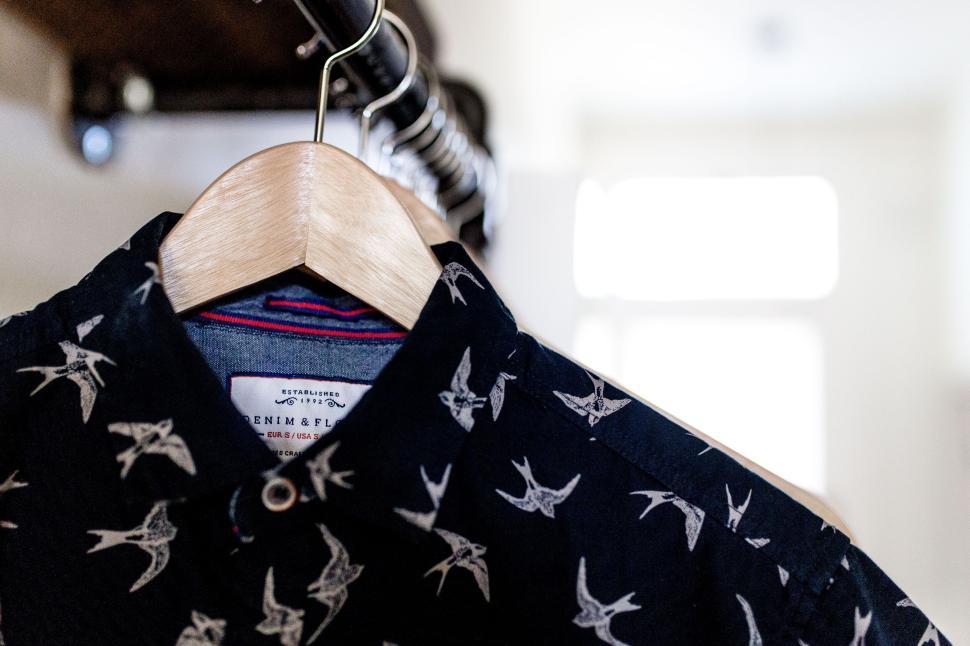 Free Image of New designer shirt with birds hanging in wardrobe. 