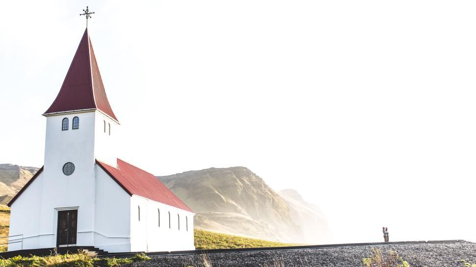 Free Image of A white church with a red roof, nestled in nature. 
