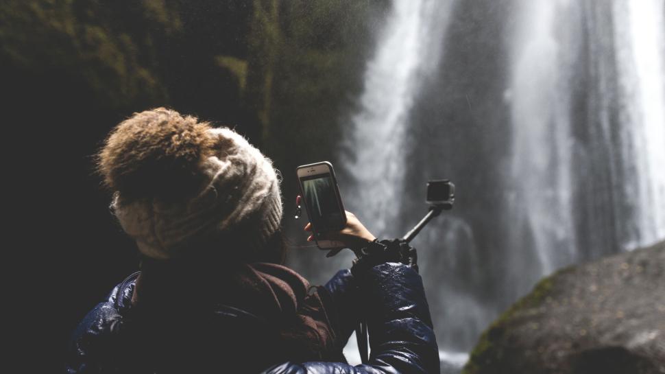 Free Image of Person taking photo of waterfall using smartphone camera. 