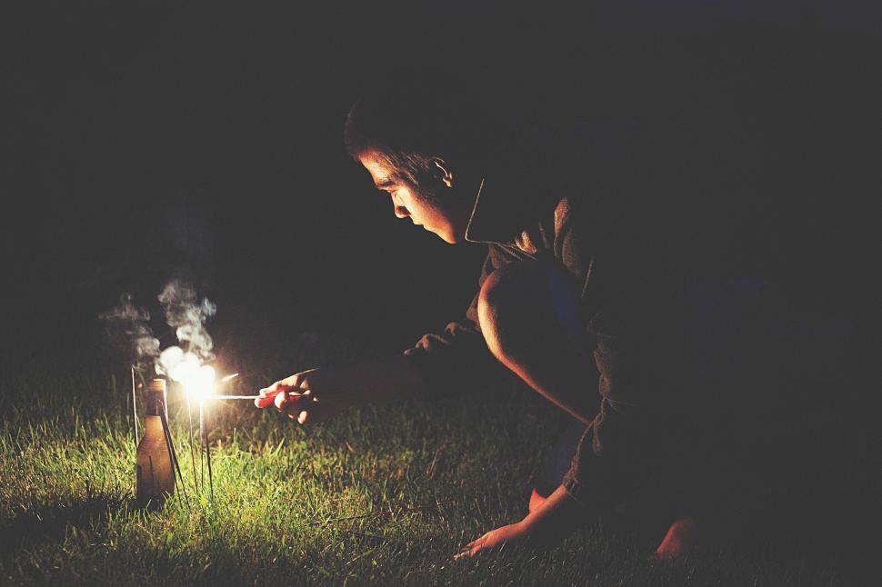 Free Image of Person lighting firework on the ground at night time. 