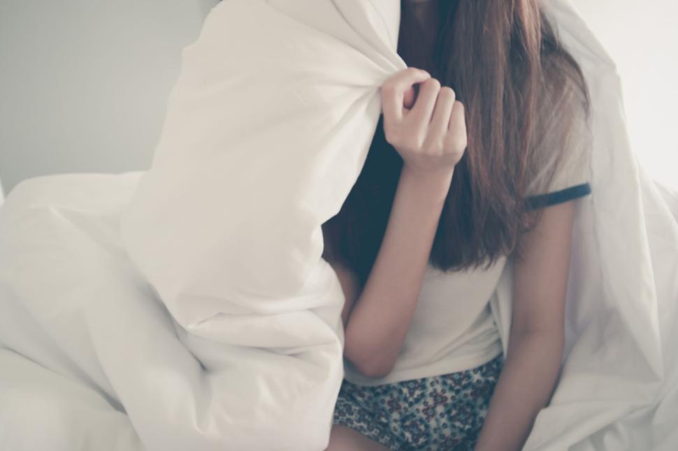 Free Image of Young woman relaxing in bed with white blanket cover. 