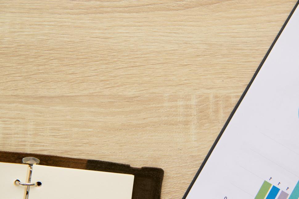 Free Image of Close-up of a notepad and graph on a wooden desk. 