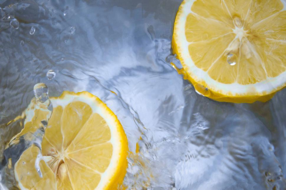 Free Image of Two lemon slices splashing in clear water creating ripples 