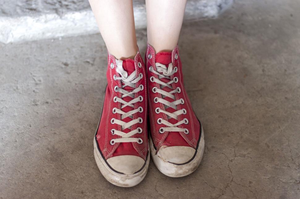 Free Image of Person wearing red converse shoes standing on concrete floor 
