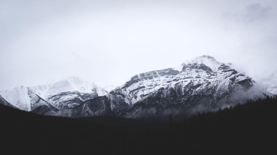 Free Image of Snow-covered mountains with mist and cloudy sky view. 