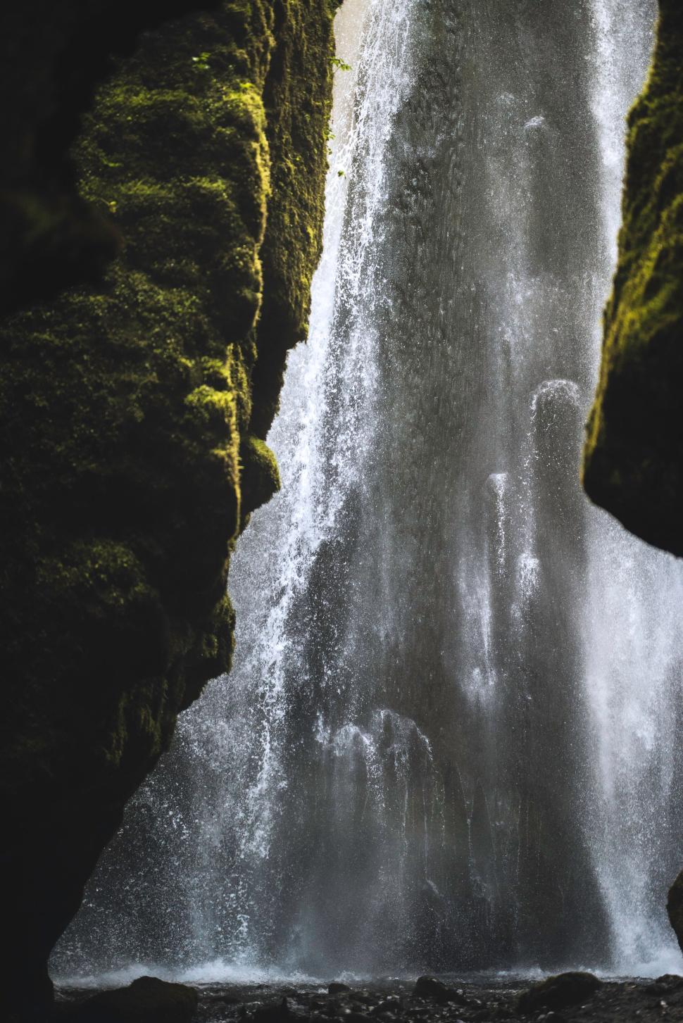 Free Image of Waterfall flowing between moss-covered rock walls. 