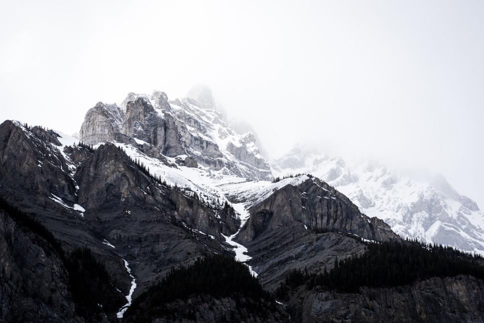 Free Image of Rocky mountain peaks under cloudy sky with snow 