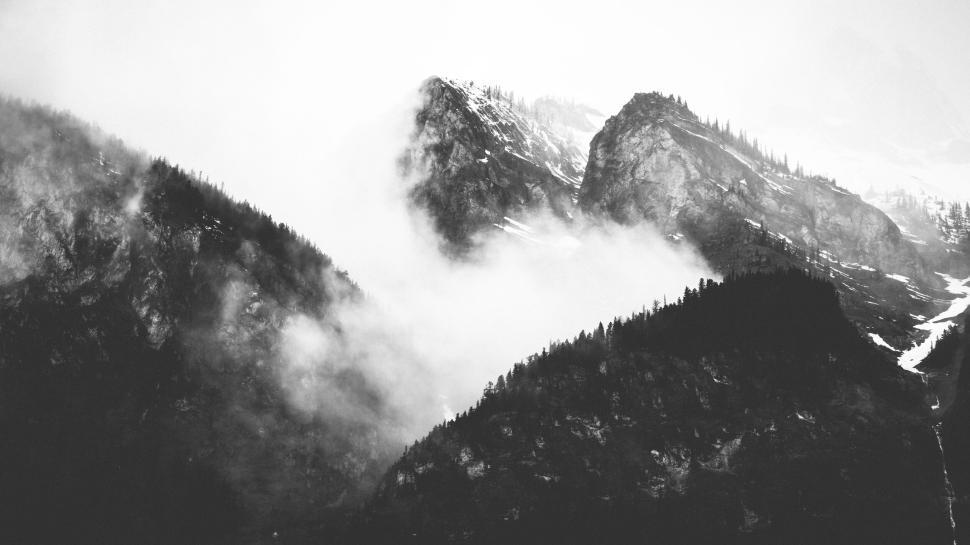 Free Image of Fog partially obscuring rugged mountainous landscape 