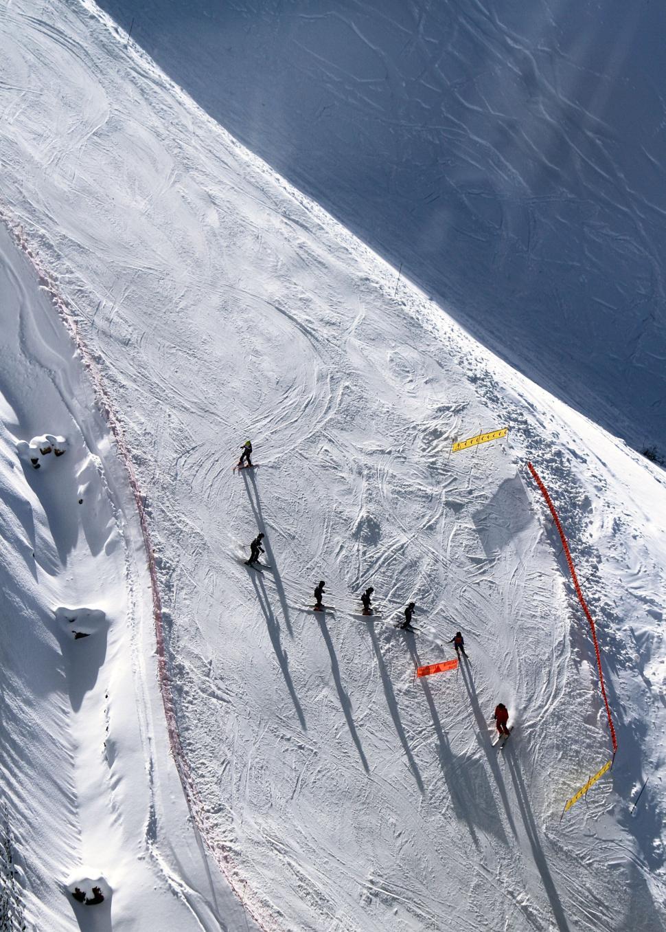 Free Image of Skiers going downhill on a snowy slope in the mountains 