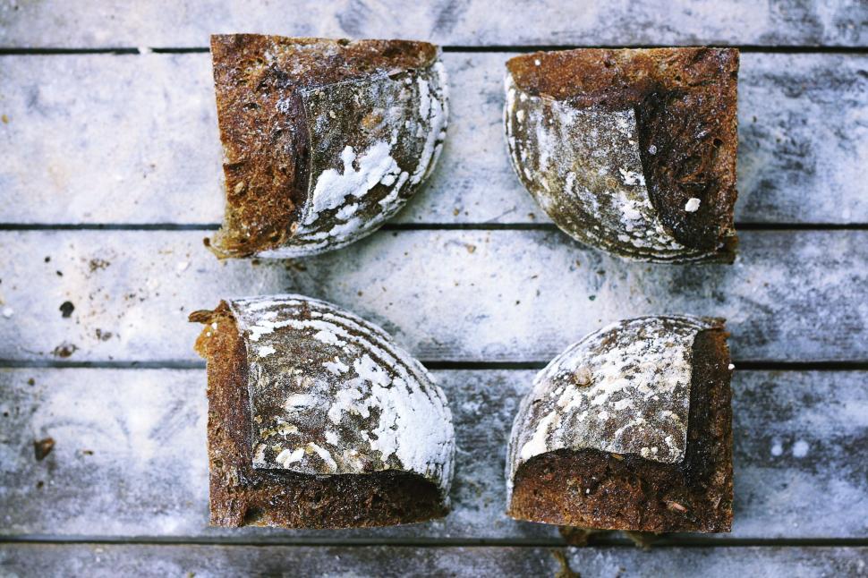 Free Image of Rustic bread loafs cut into quarters on a wooden surface 