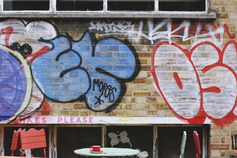 Free Image of Graffiti wall with red chairs and table in foreground. 