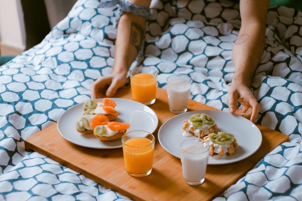 Free Image of Breakfast tray with juice, toast, waffles, in bed setting. 
