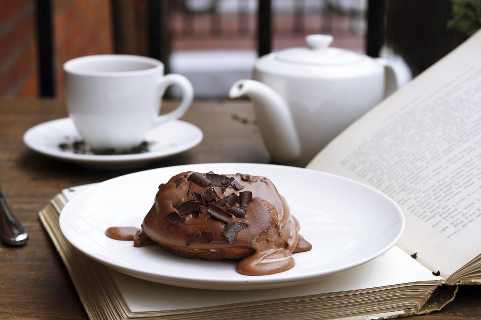 Free Image of Chocolate pastry with tea and book on a wooden table. 