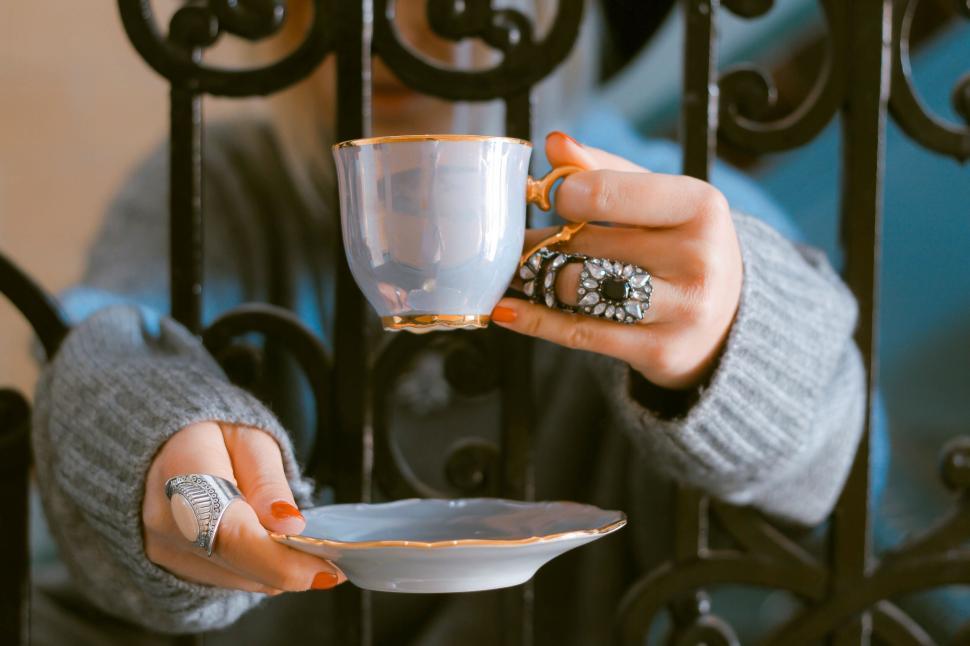 Free Image of A hand adorned with rings holding a vintage teacup 