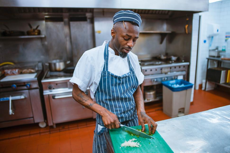 Free Image of Chef chopping vegetables in a professional kitchen 