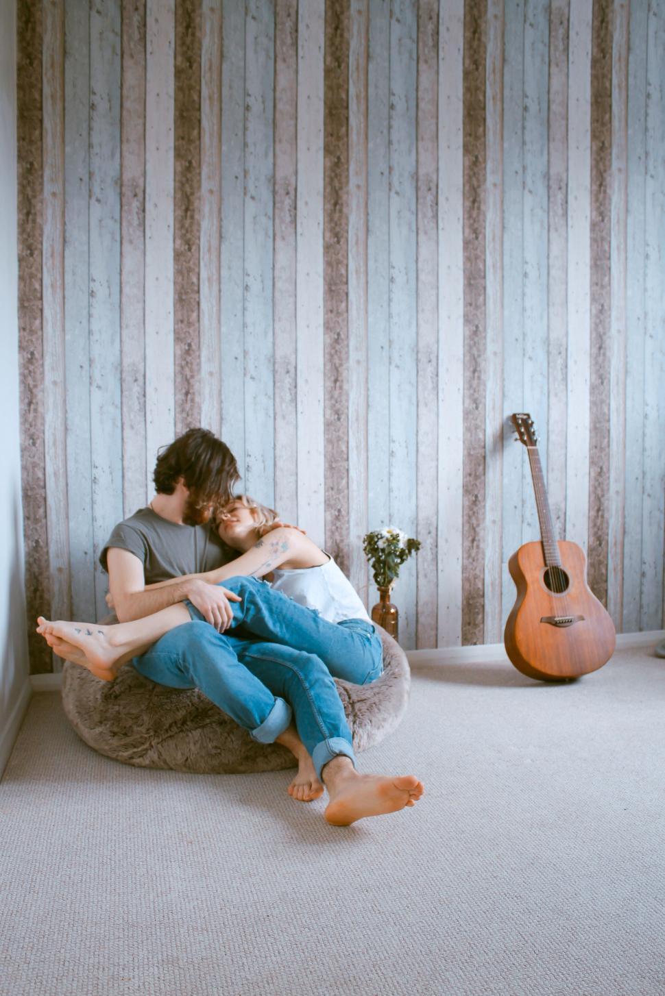 Free Image of Couple embracing on a cozy bean bag at home 