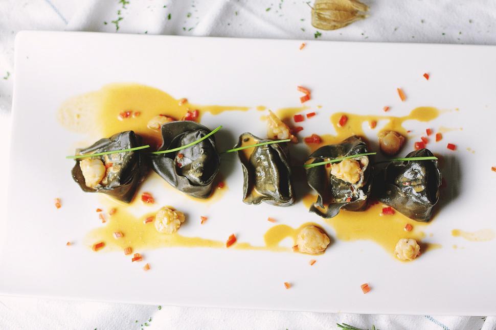 Free Image of Five gourmet stuffed shells on white plate with sauce. 