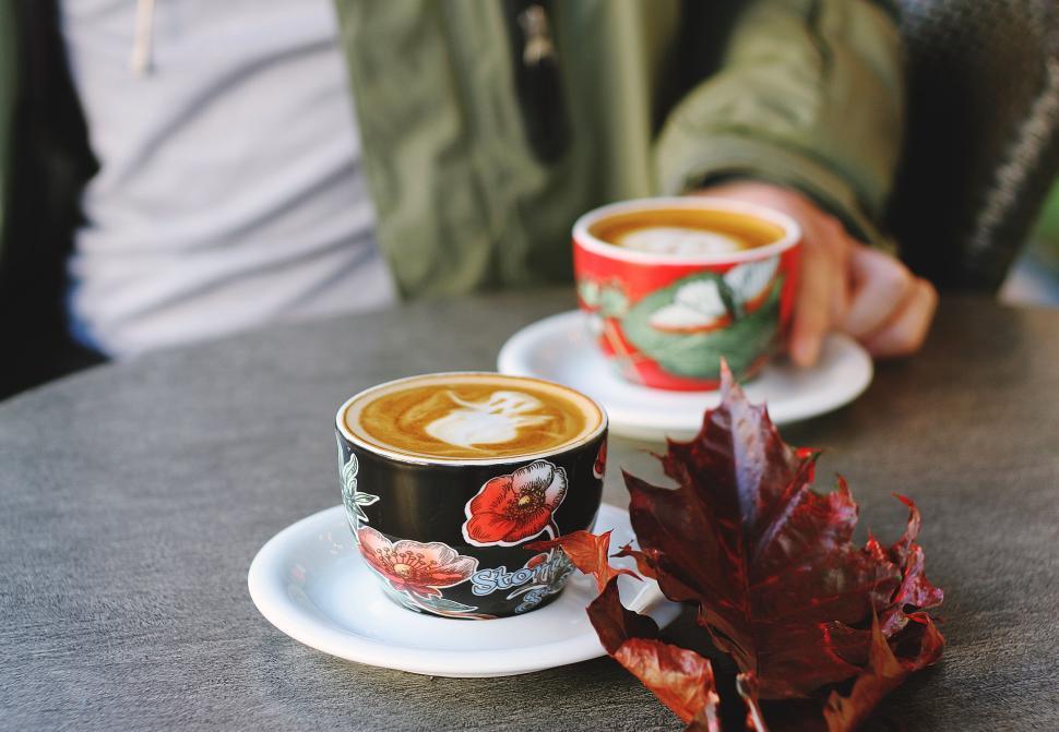 Free Image of Two coffee cups on table, person in background holding one. 