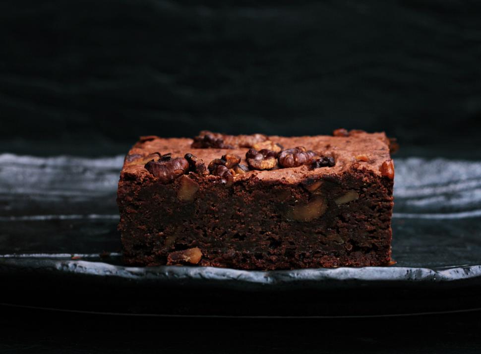 Free Image of Chocolate brownie with nuts on a dark plate. 