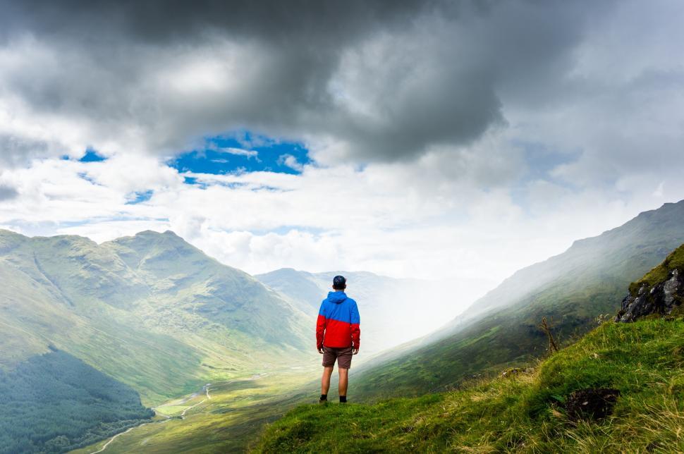 Free Image of Hiker looking over a vast valley with dramatic cloudscape 