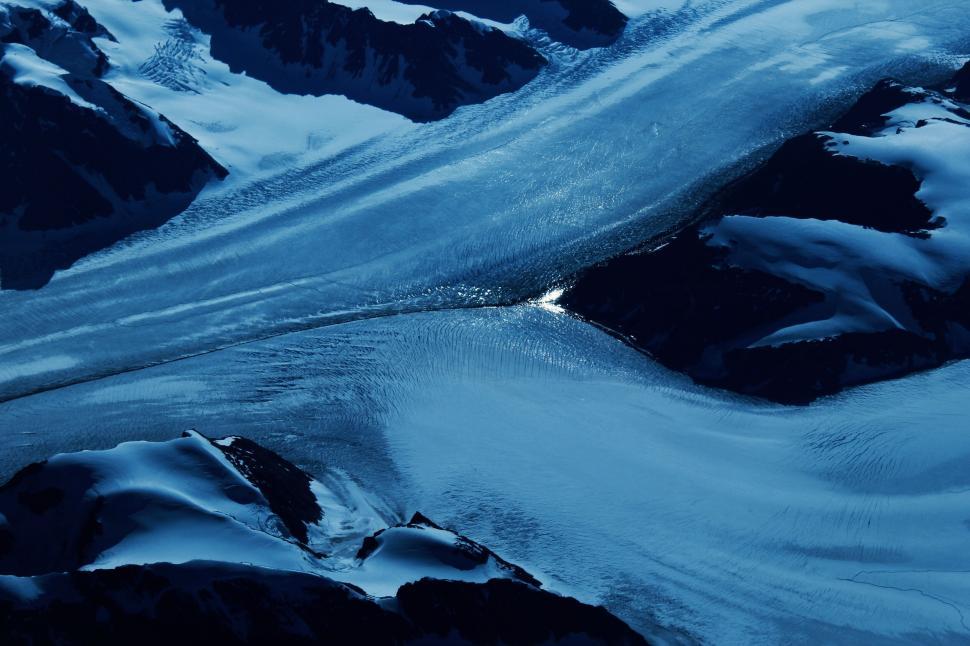Free Image of Aerial view of a glacier flowing through mountainous terrain 