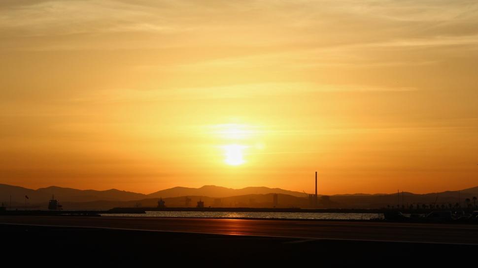 Free Image of Serene sunset over water body with distant mountains 