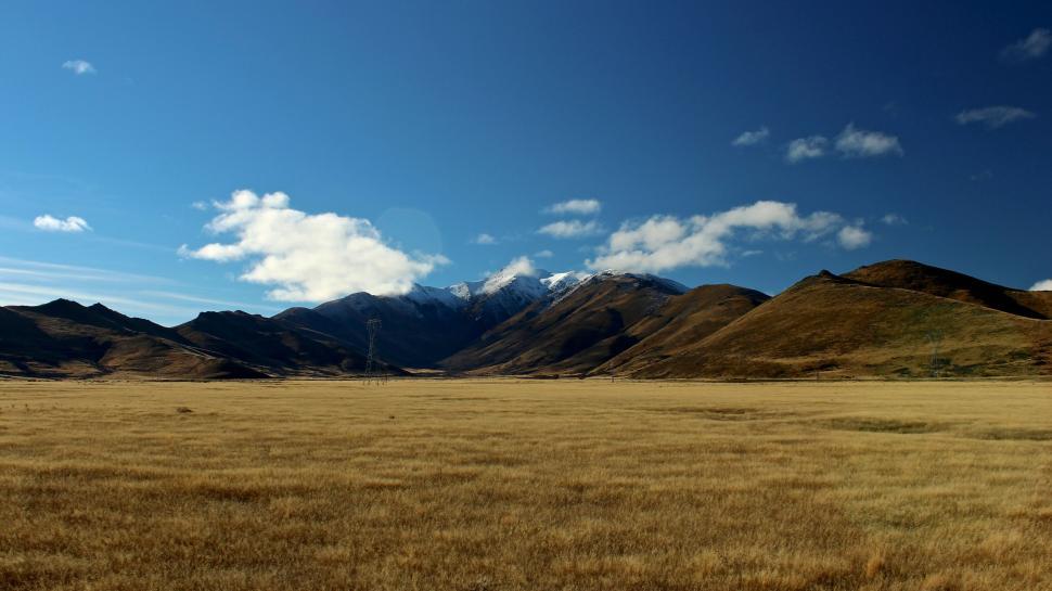Free Image of Vast dry field with mountains under blue sky 