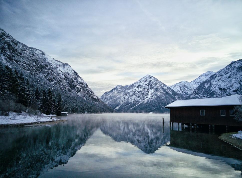 Free Image of Snowy mountains with a cabin and a lake reflecting them 