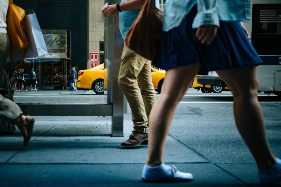 Free Image of People walking on urban sidewalk with yellow taxi in view 