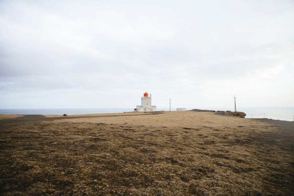 Free Image of Isolated lighthouse with red roof against cloudy sky. 