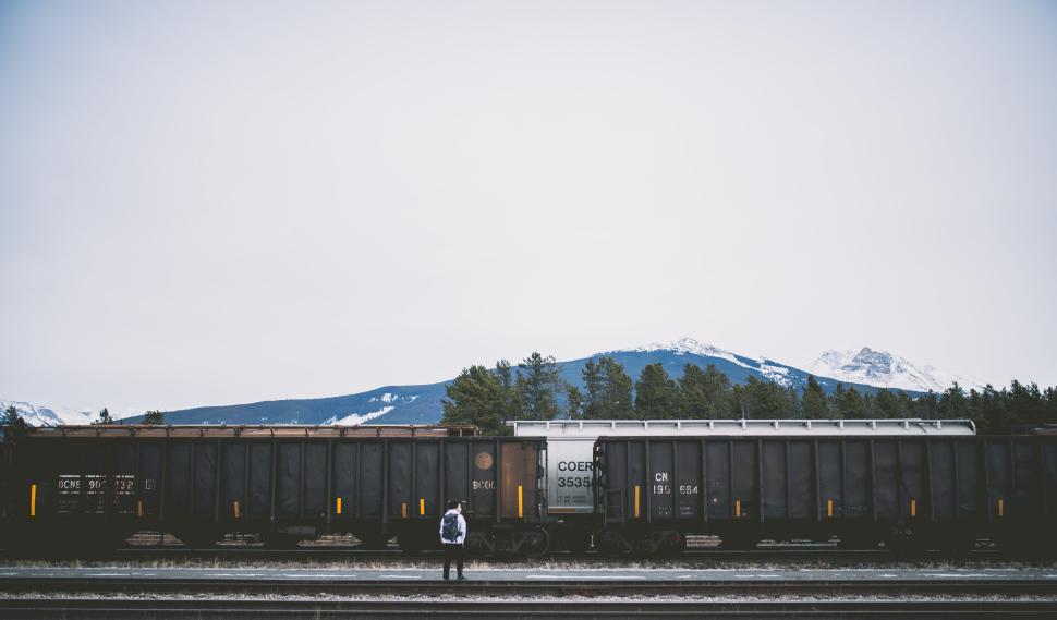 Free Image of Train in front of mountainous landscape with lone figure. 