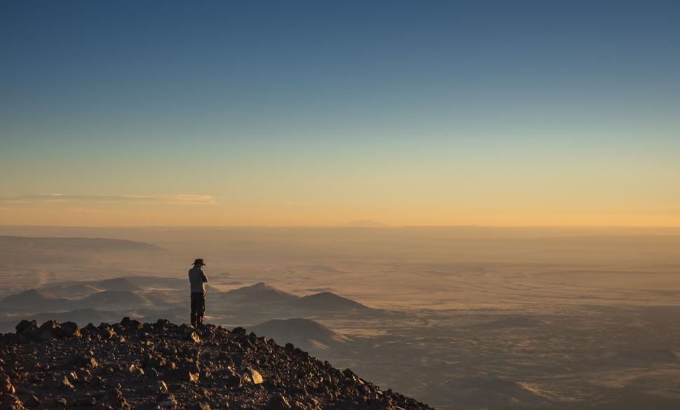 Free Image of Hiker stands on rocky peak overlooking vast horizon. 