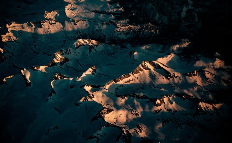 Free Image of Aerial view of snow-capped mountains during sunset hour. 