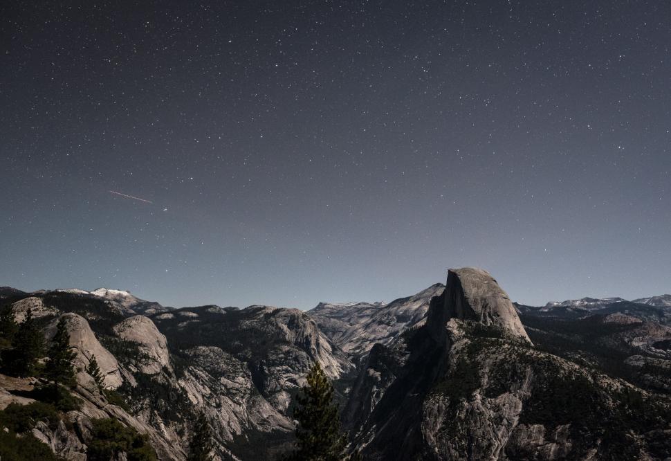 Free Image of Starlit night sky over expansive mountain valley and cliffs. 
