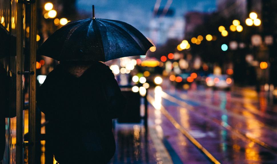 Free Image of Person with umbrella on rainy city street at night. 