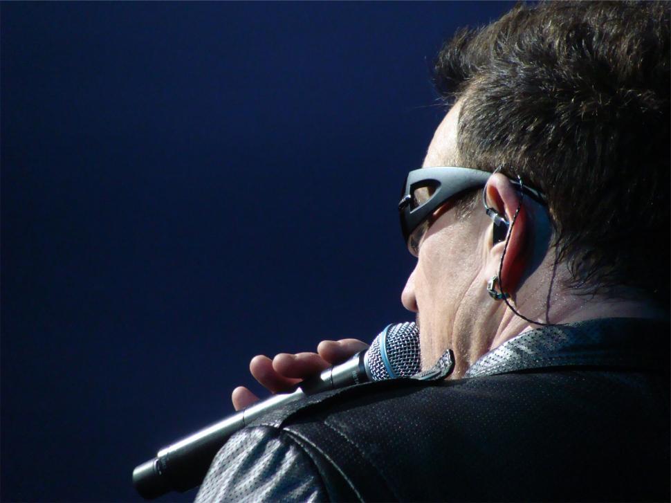 Free Image of Singer on stage with microphone and blue lit background. 