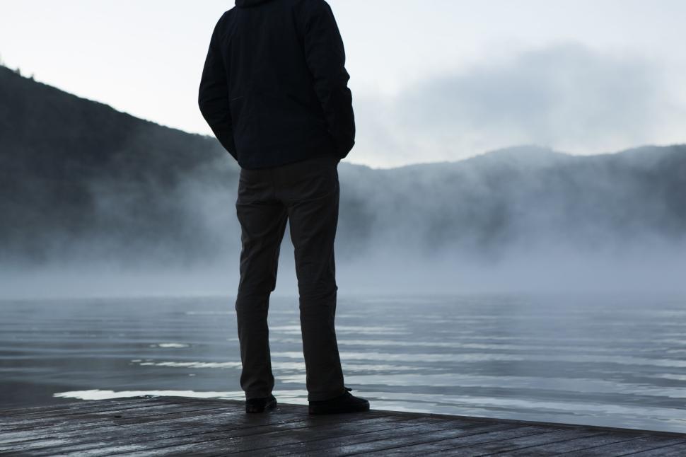 Free Image of Man standing by the lake on a misty early morning 