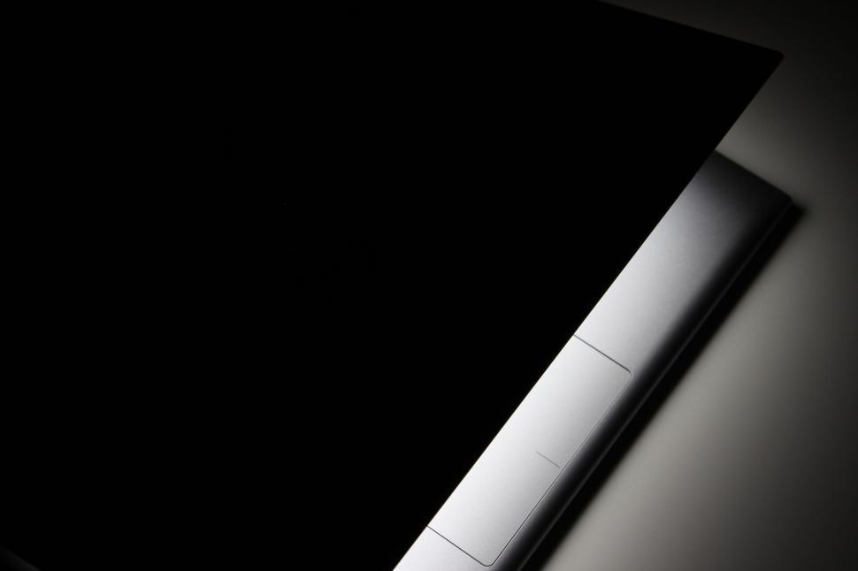 Free Image of Partially opened laptop revealing light in dark setting. 