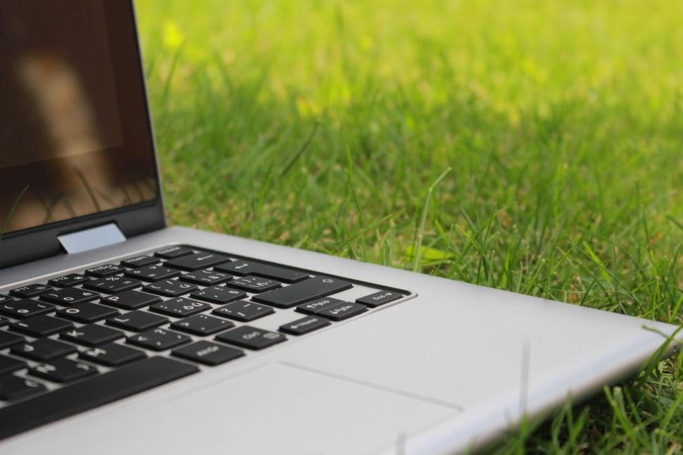 Free Image of Laptop resting on grass in outdoor setting under sun 