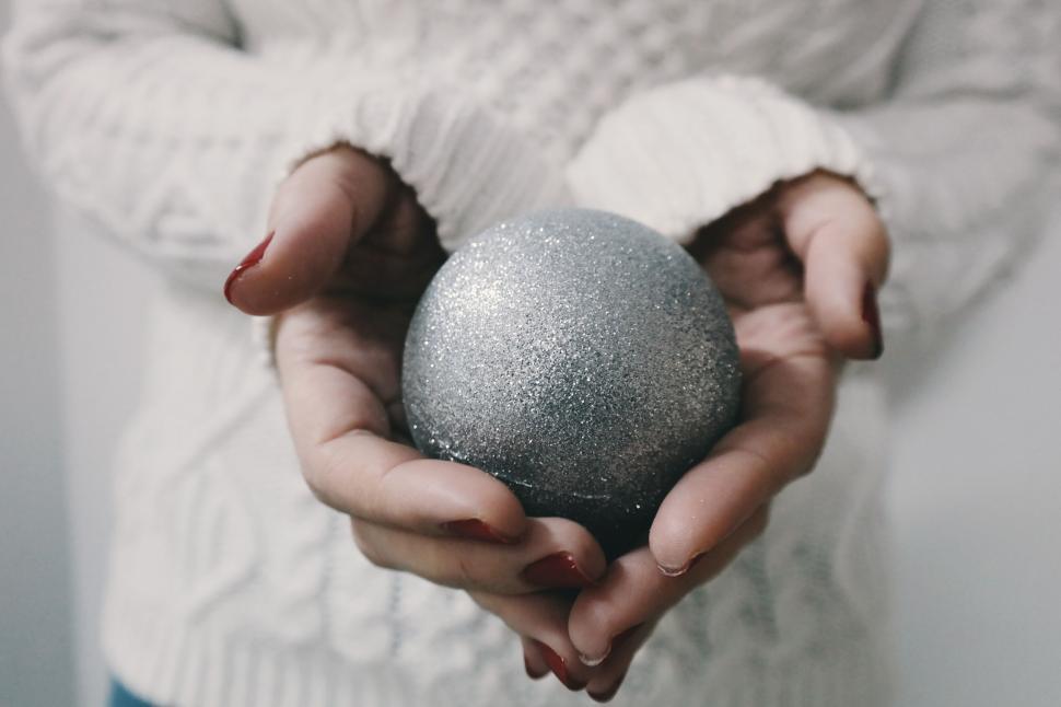 Free Image of Hands holding a sparkling silver ball delicately. 