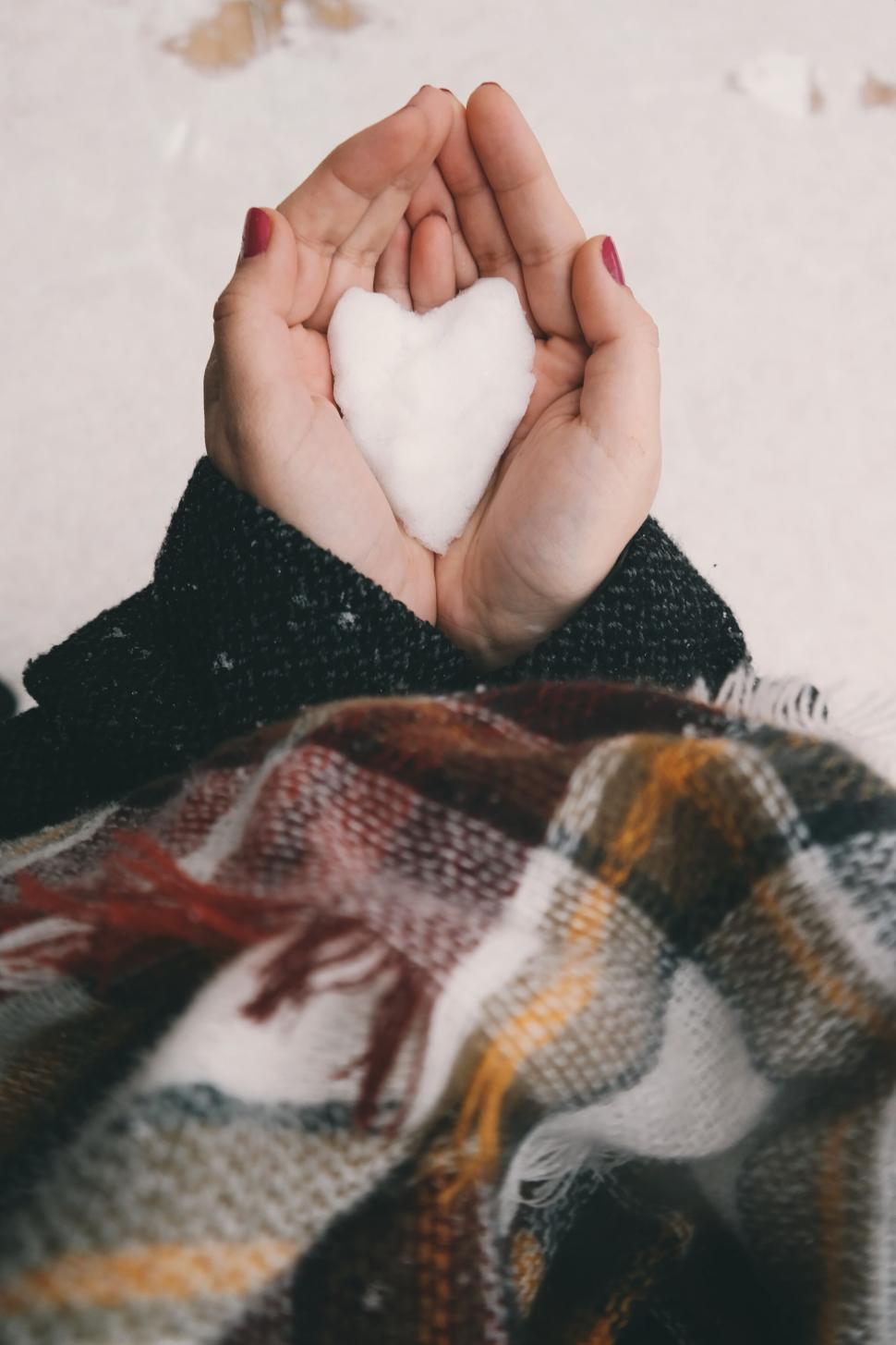 Free Image of Hands holding a heart-shaped snow piece in winter 