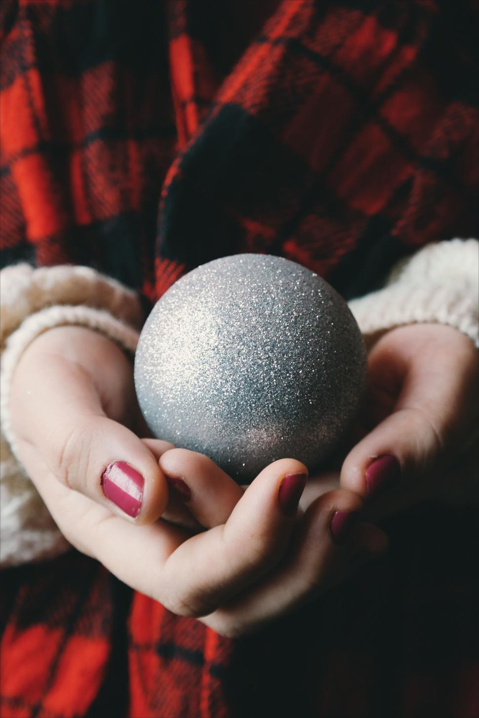 Free Image of Person holding a glittery silver Christmas tree ornament 