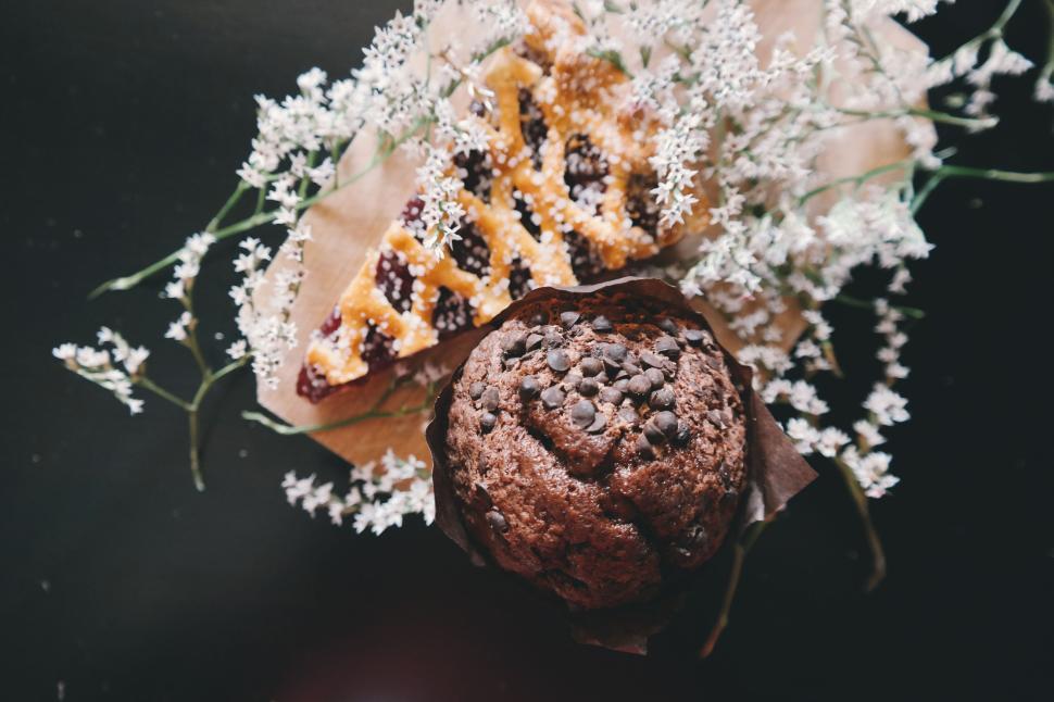 Free Image of Chocolate muffin and decorative pastry with white flowers. 