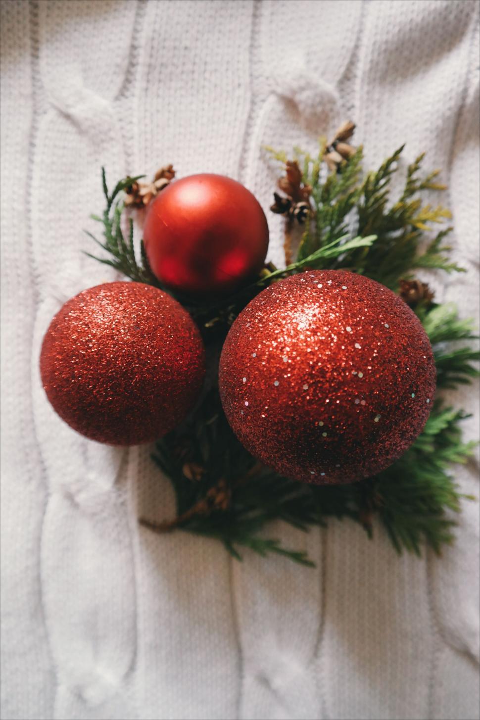 Free Image of Three red baubles on evergreen branches for Christmas 