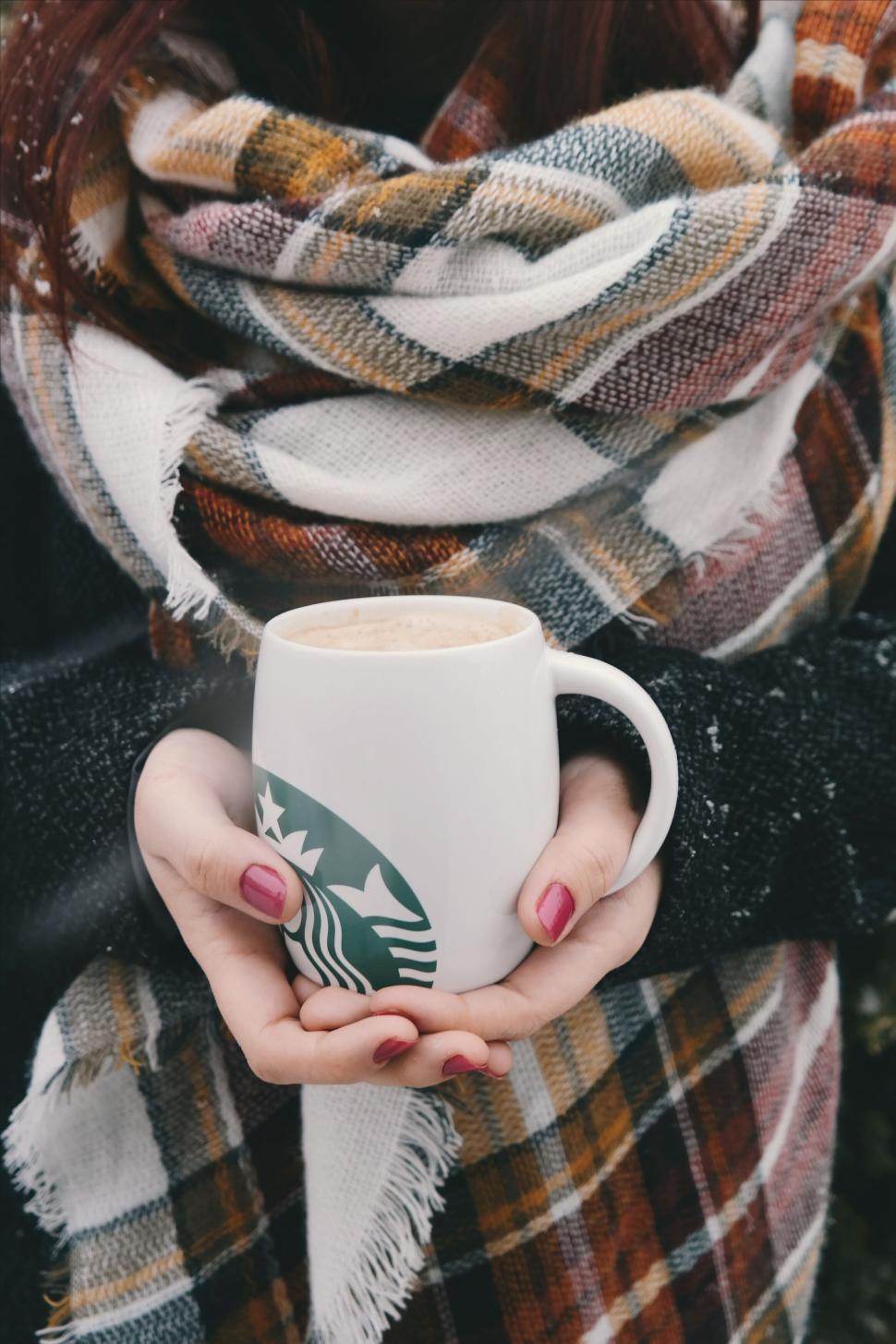Free Image of Woman holding a Starbucks coffee cup with scarf 