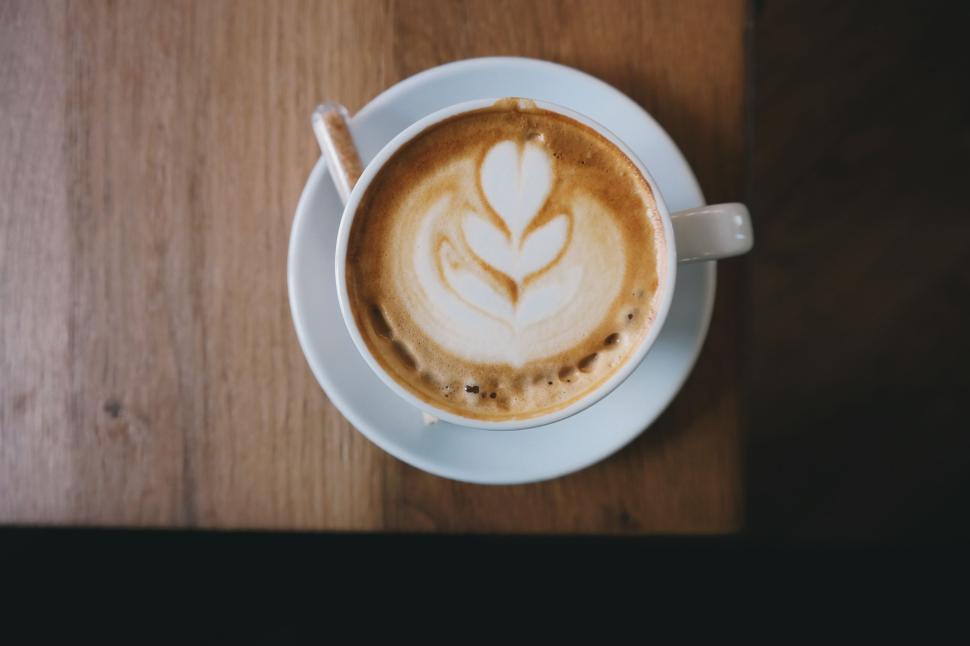 Free Image of Latte art coffee in a white cup on a wooden table 